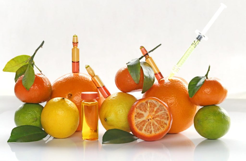 Vials of vitamin injects placed artistically next to oranges, lemons, and limes
