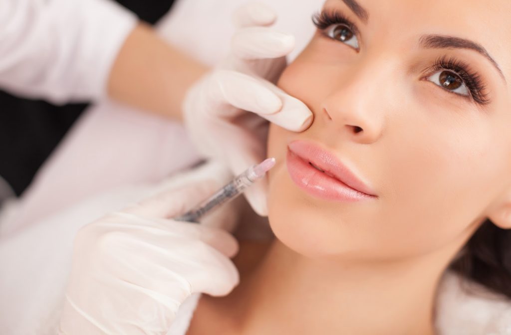 Young happy woman receiving botox lip filler from professional.