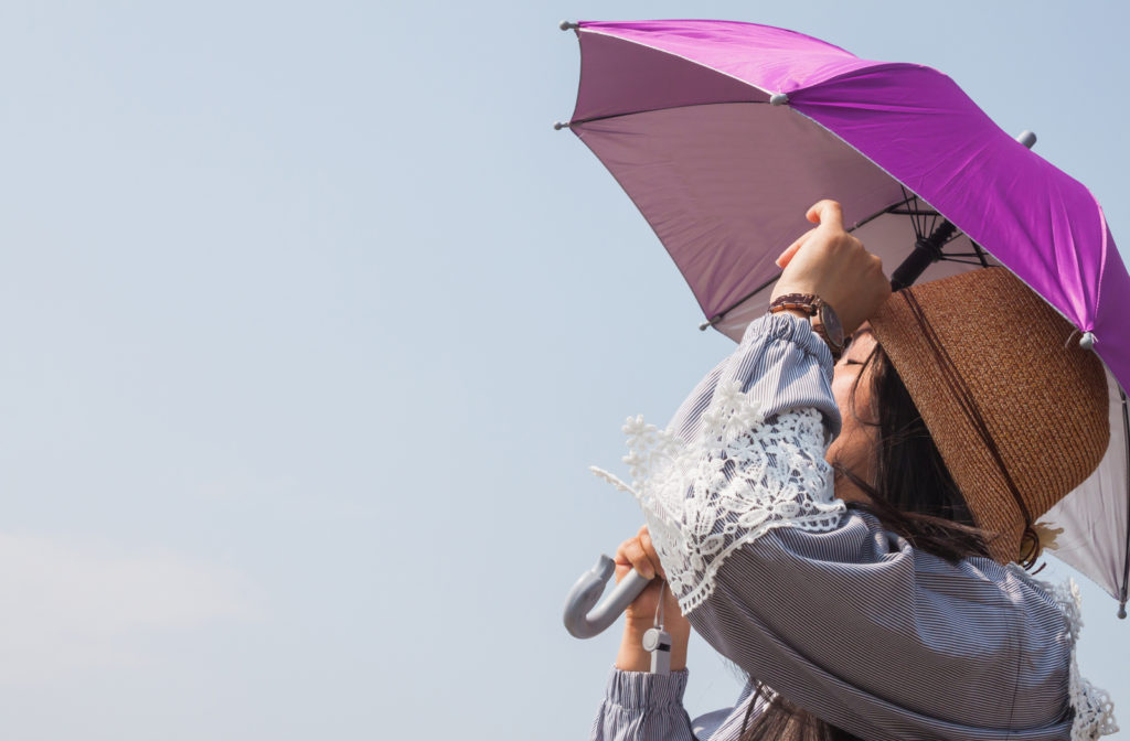 Woman holding umbrella and wearing long sleeve shirt to avoid sunlight