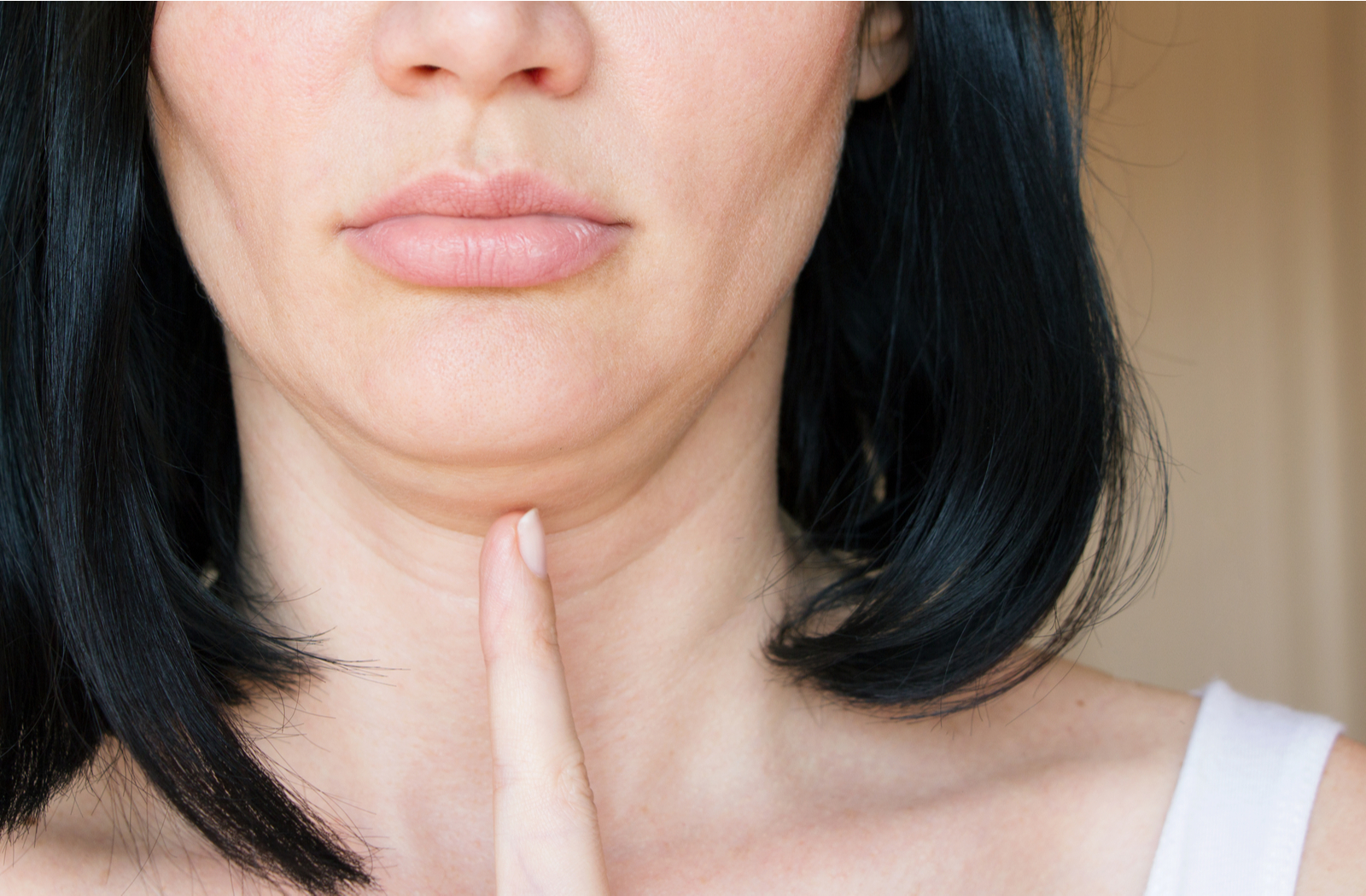 Close up of women pointing to her chin with double chin visible