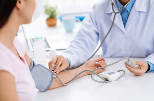A younger woman has her blood pressure checked by a medical professional.