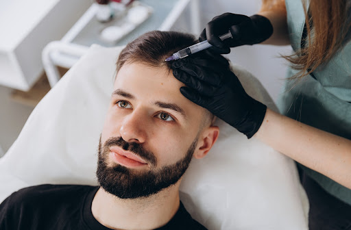 A young adult man receives a PRP injection at a medical cosmetics clinic.