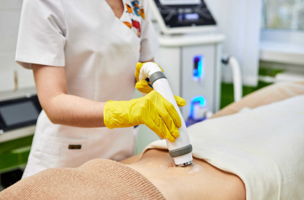 Technician performing laser skiing tightening treatment on female patient.