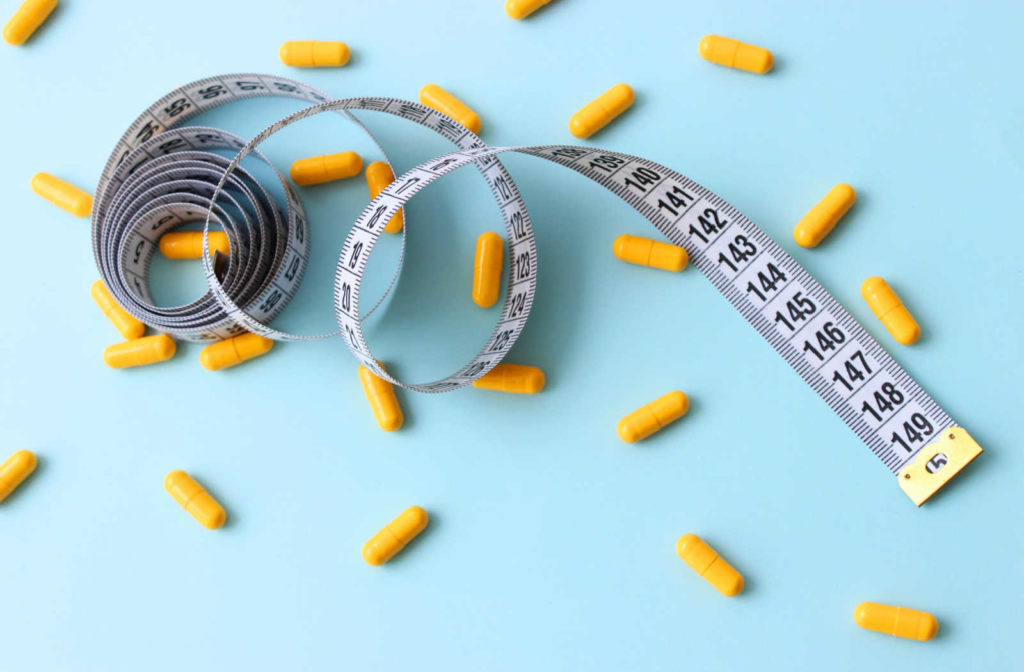 Wound up measuring tape surrounded by yellow supplements in a blue background.