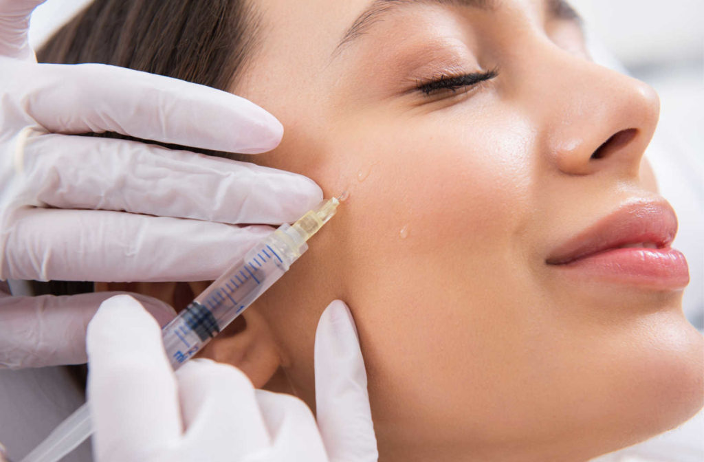 A female patient has a filler injected into upper cheek area.