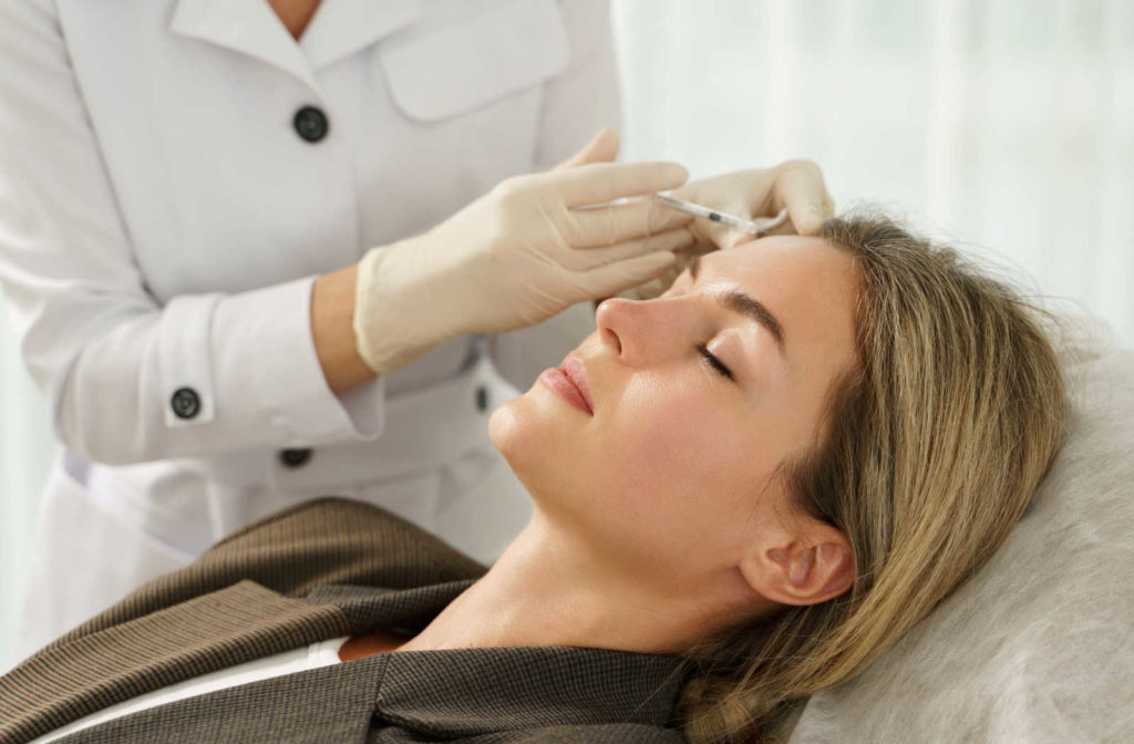 A woman receiving injections to her forehead.