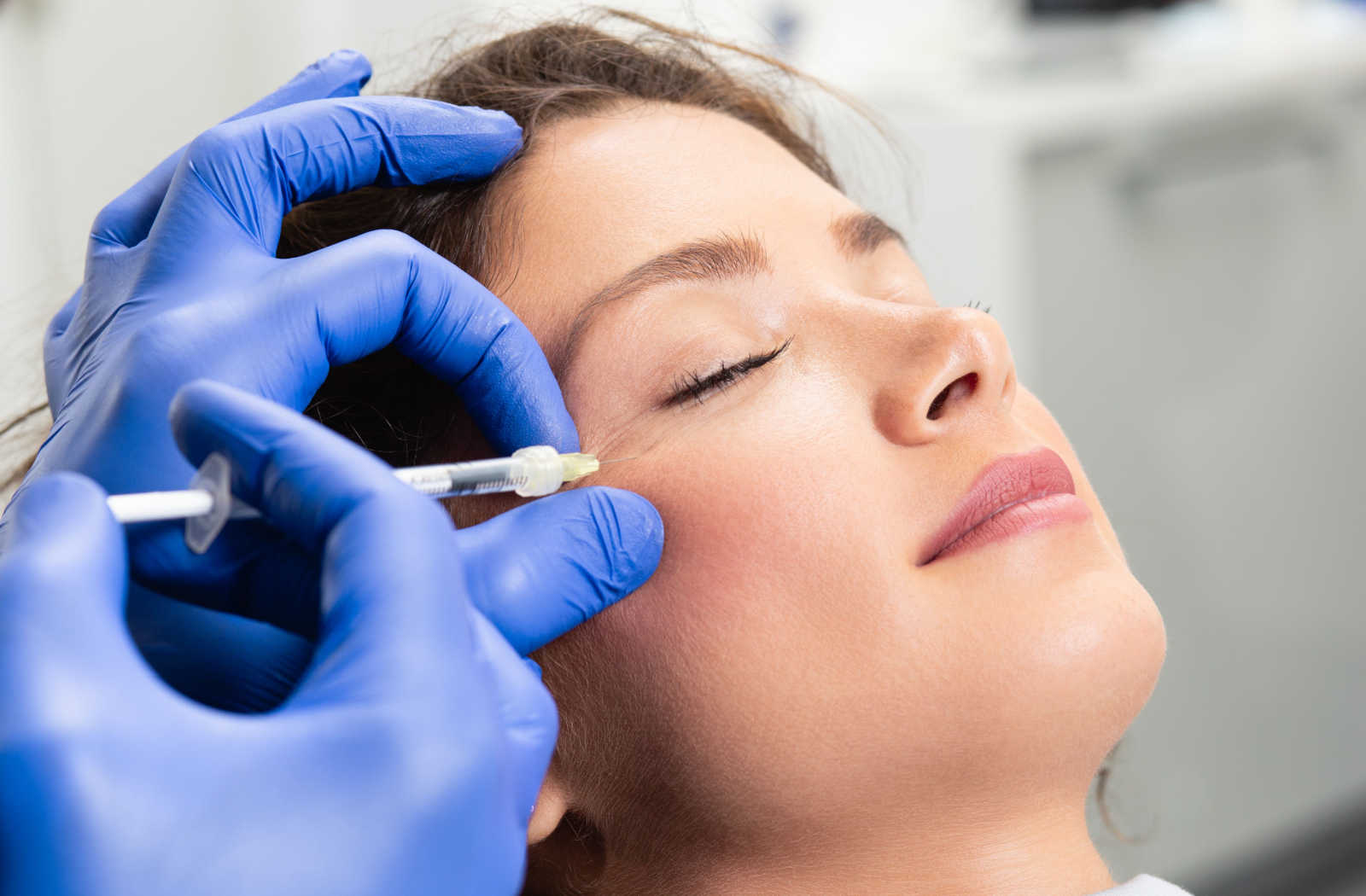 A woman receiving a PRP injection next to her eye.