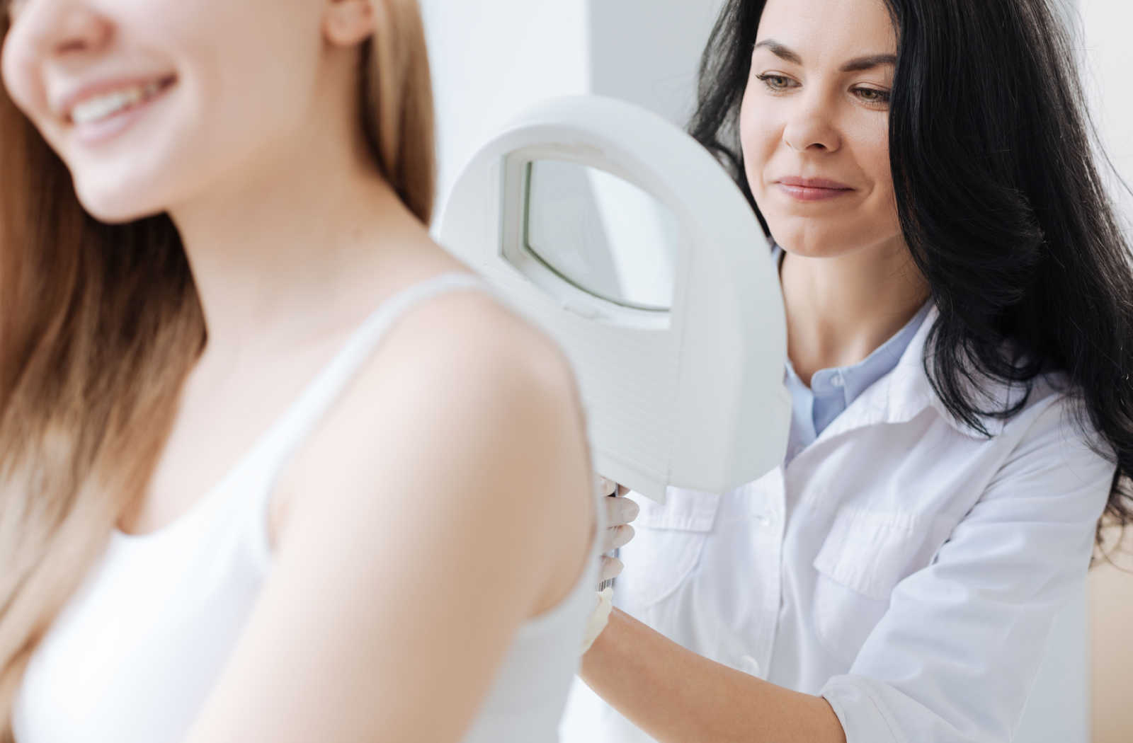 A dermatologist inspecting a female patient's back.