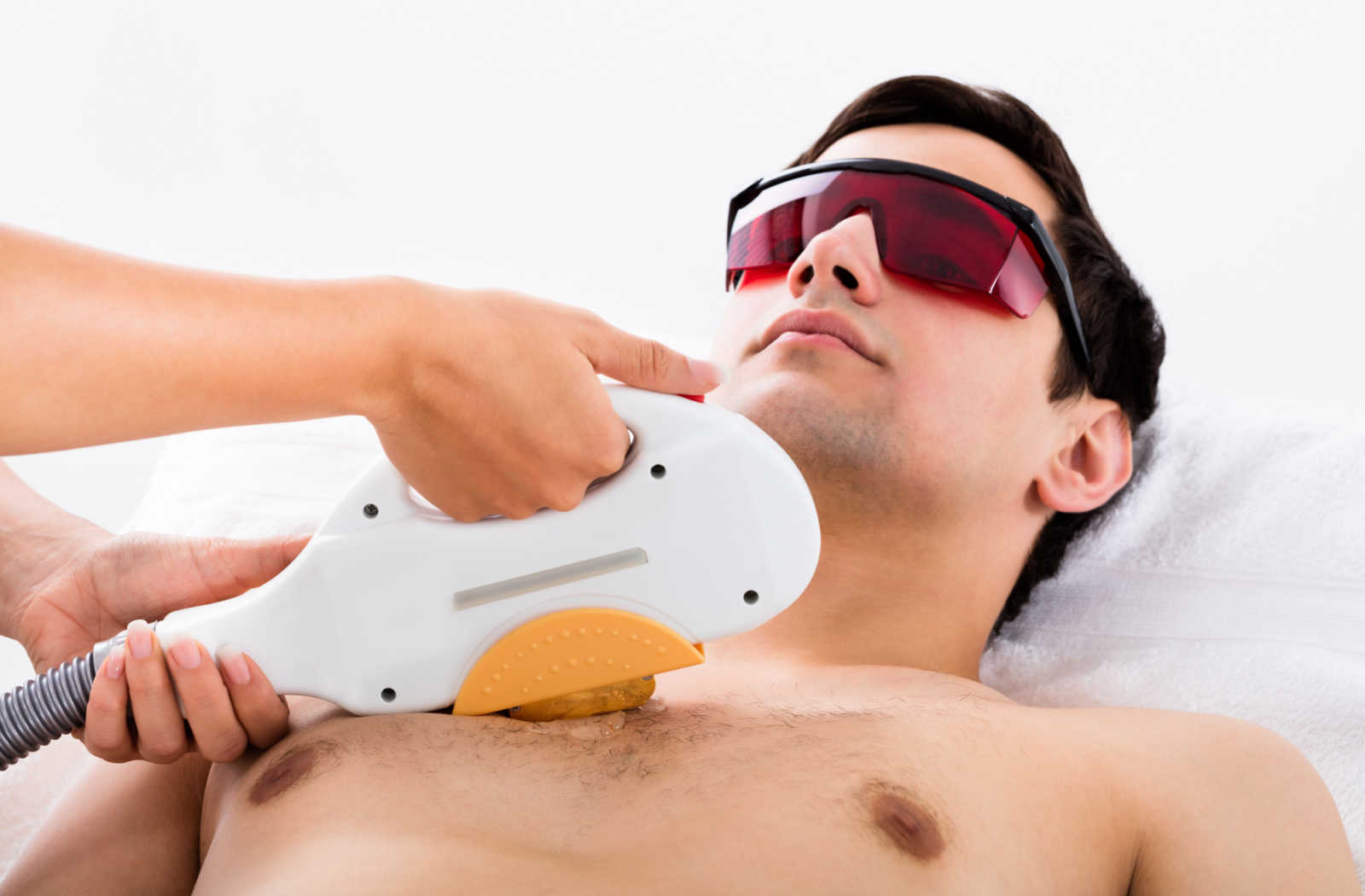 A young man is undergoing laser treatment to remove hair on his chest.
