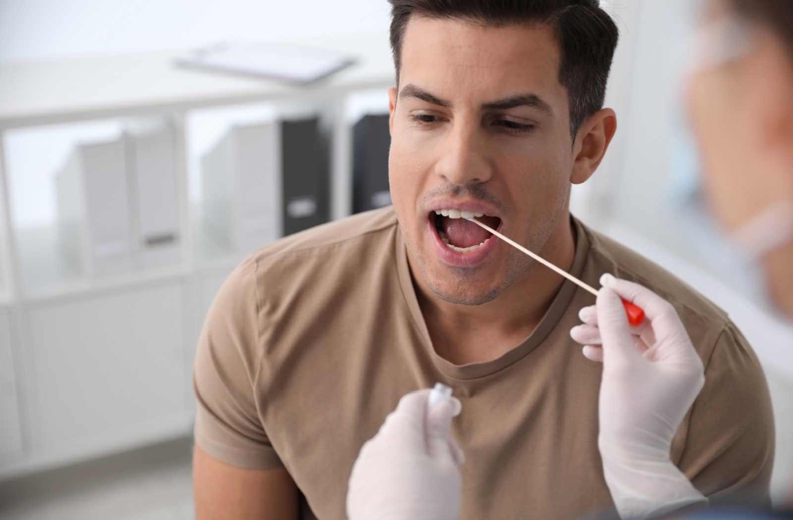 A man getting swabbed for genetic testing inside a clinic.