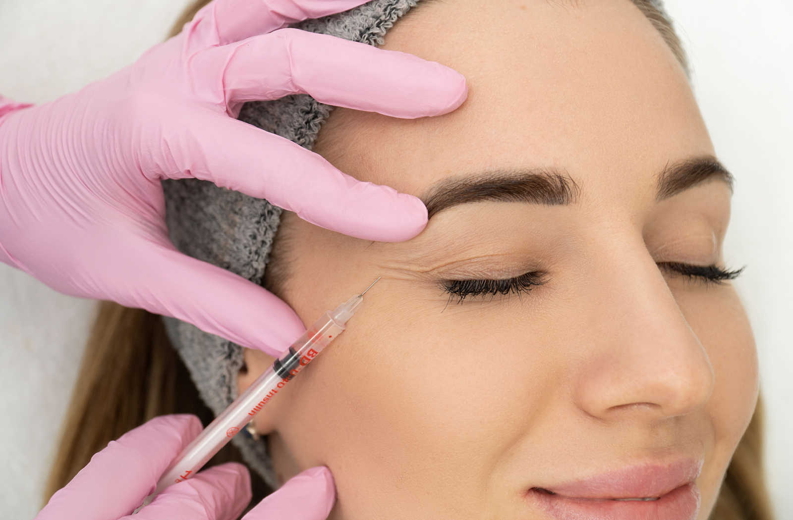 Expert cosmetologist injecting Botox treatment with close-up of hands.