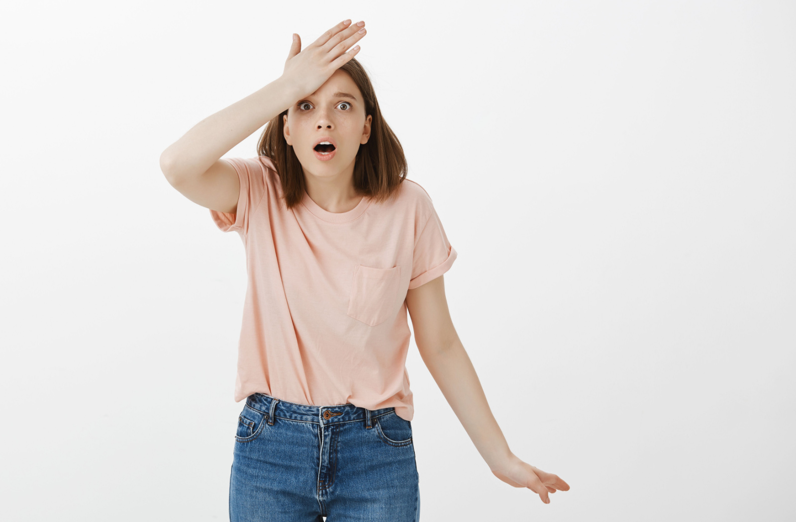 A young woman shocked and remembered that she forgot something, holds her forehead with her right hand.