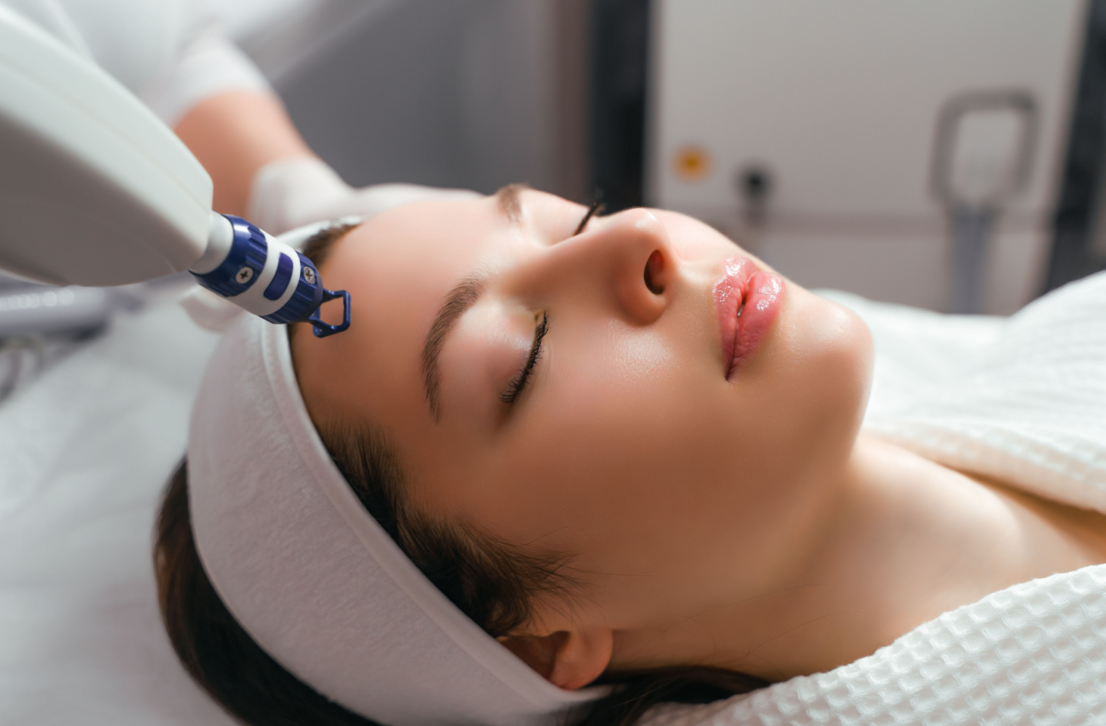 A cosmetologist performing a Laser Skin Resurfacing on a woman using a specialized equipment.