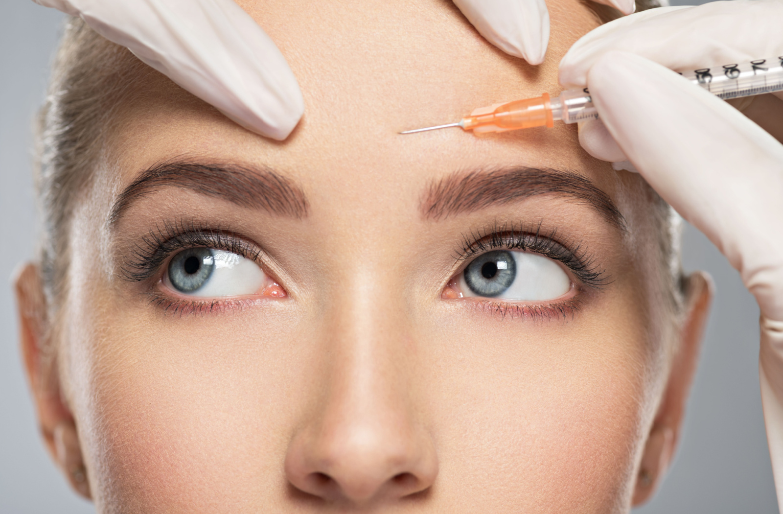 Close up of a woman getting botox injected above the center of her brow line.