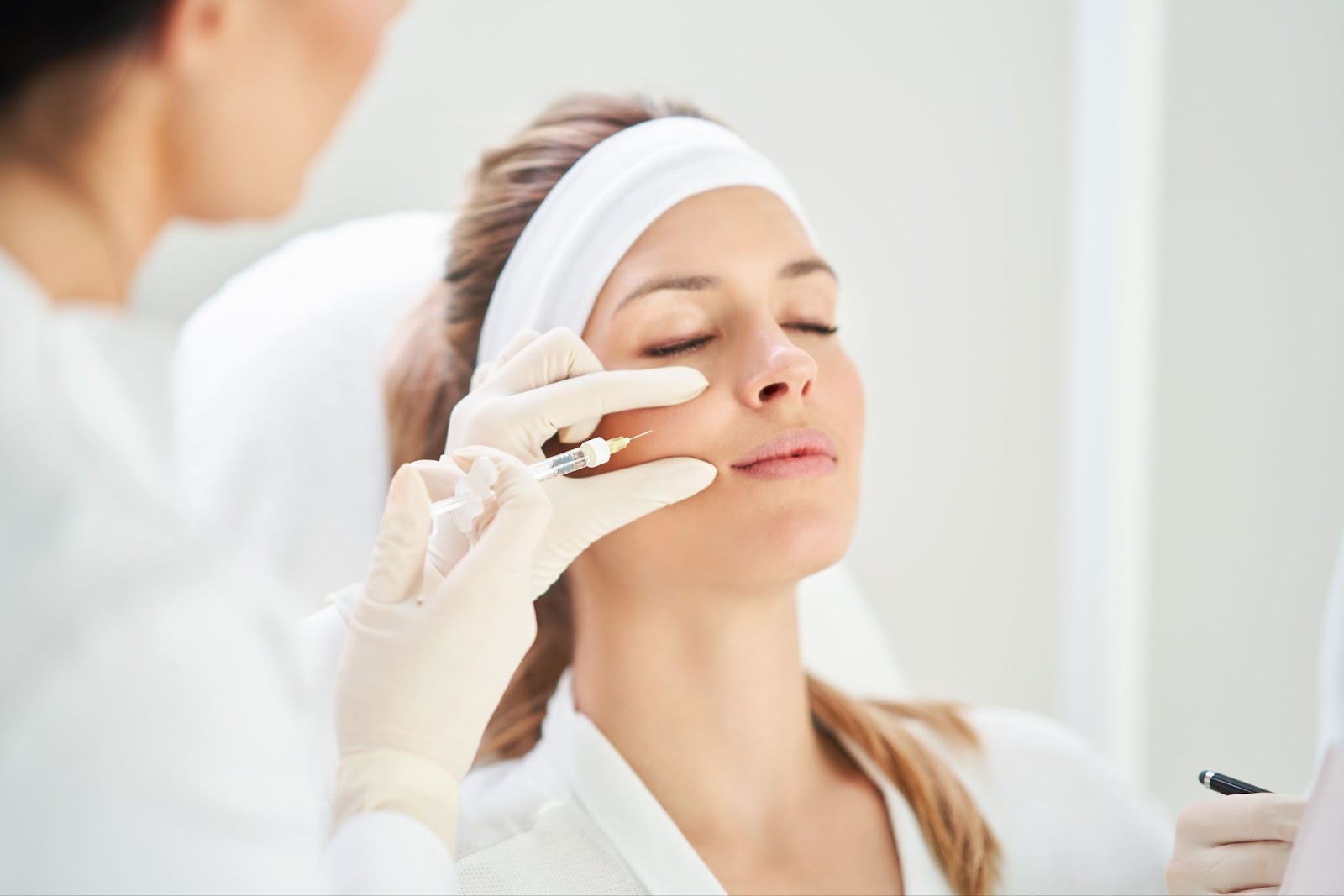 A woman is getting botox administered at a medical aesthetics clinic.