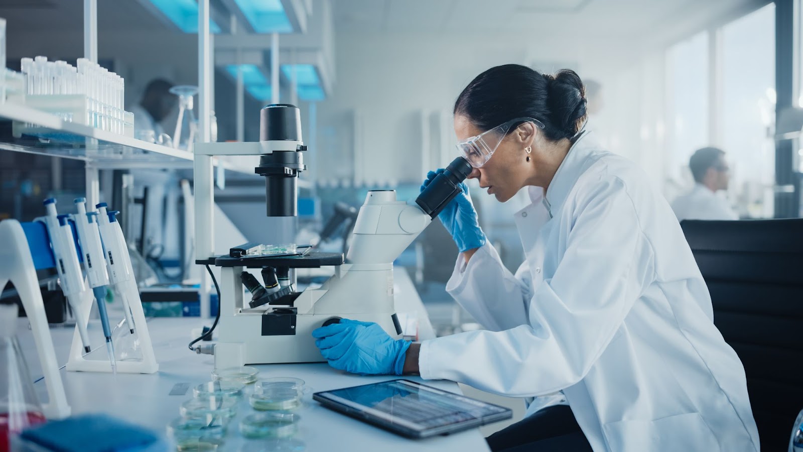 A female scientist in a laboratory using a microscope to examine someone's DNA.