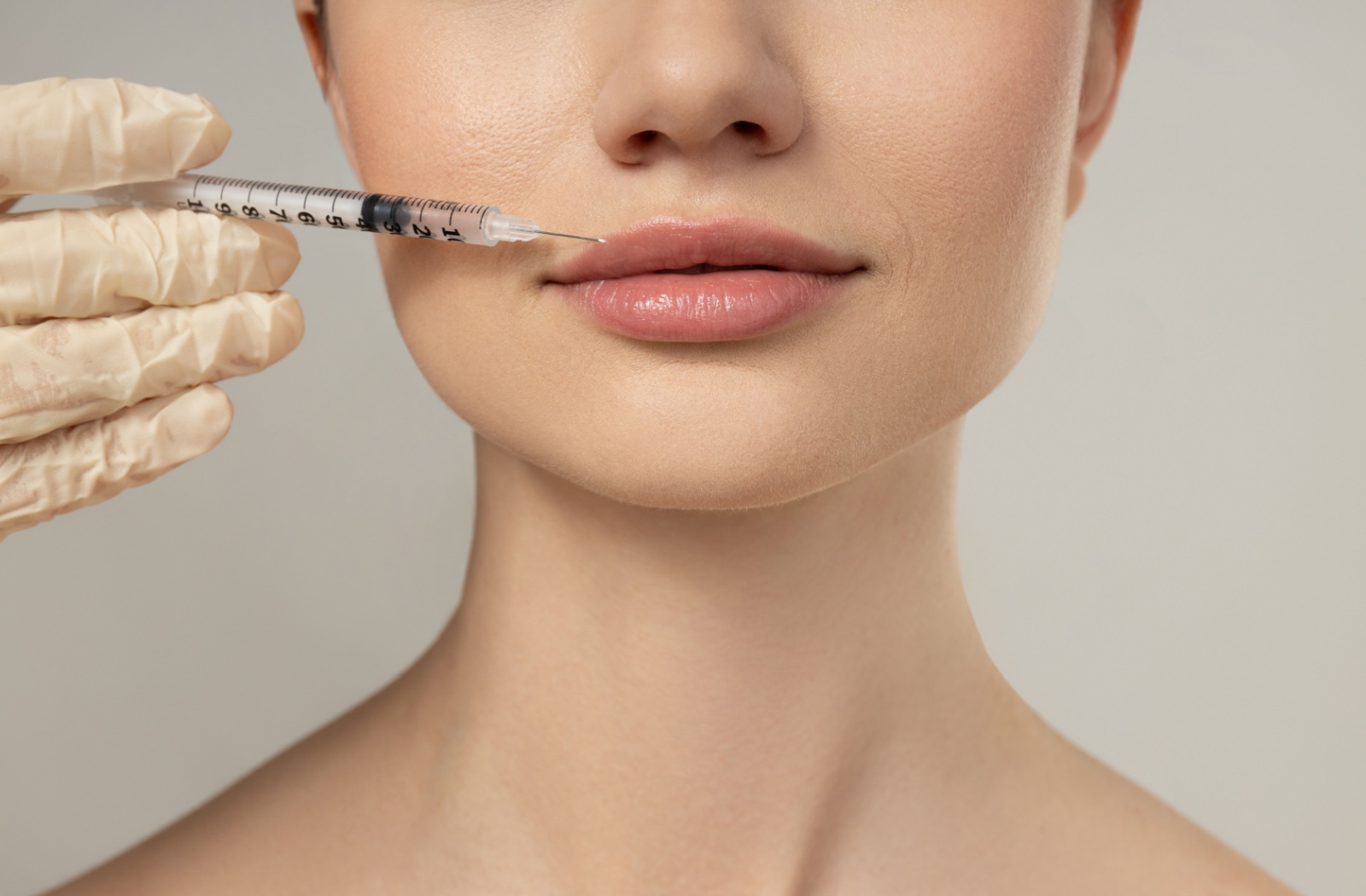 A close-up of a hand carefully injecting a person's top lip with botox.
