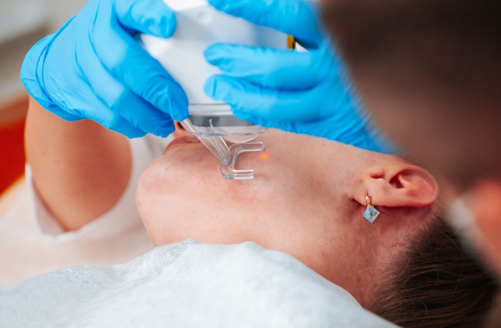 A technician gently uses a laser device on their client's skin to target and reduce uneven texture.
